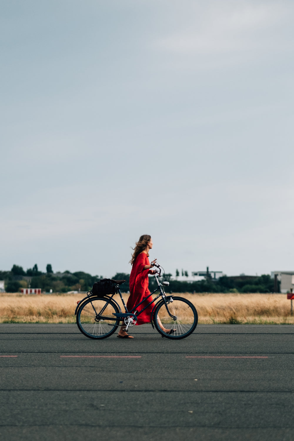 person-in-red-dress-walks-bicycle-down-the-road