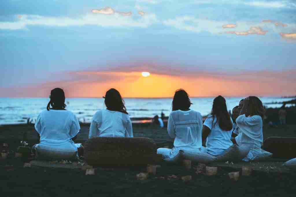 women sitting on the beach drinking cacao drinks in cacao ceremony